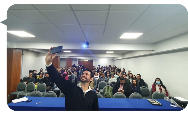 Jorge Fuchs se toma una selfie con una audiencia llena en un auditorio durante su conferencia.