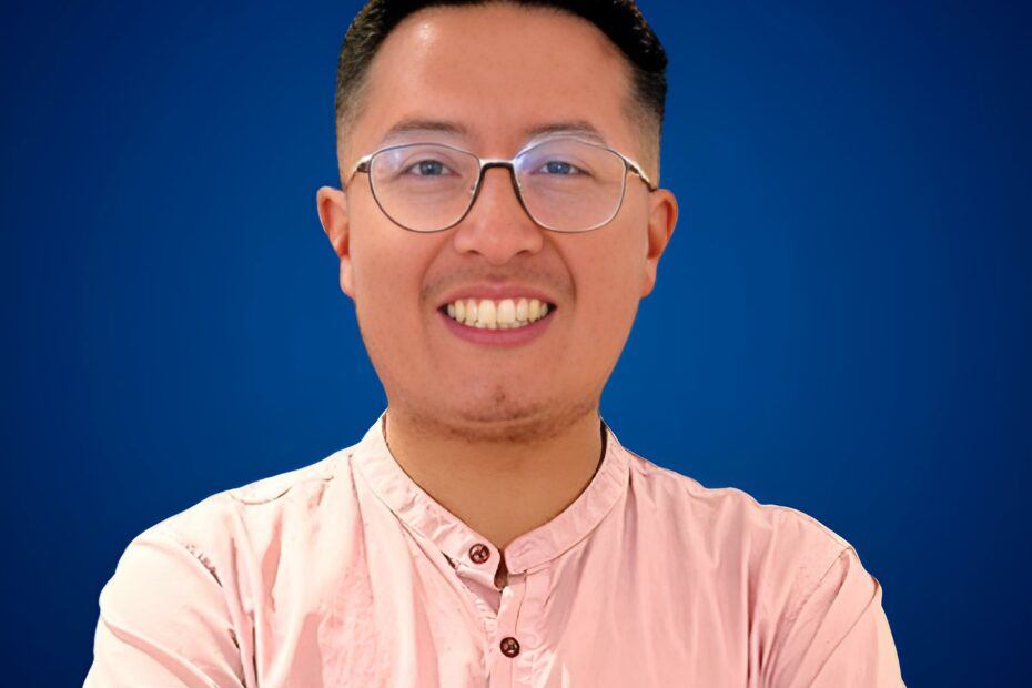 Jaime Vaca Guzmán con camisa rosa, sonriendo frente a un fondo azul