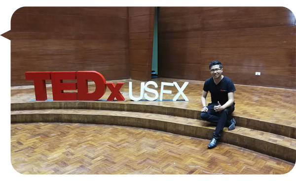 Jaime Vaca Guzmán sentado junto al logo de TEDxUSFX en un escenario de madera después de su participación en el evento.